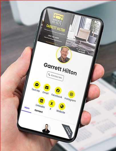 A white male left hand holding a mobile phone tipped 5 degrees, displaying a Realtor's digital Hub on the screen.